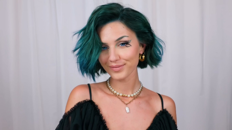 A Person with Short, Teal-Colored Hair Smiles