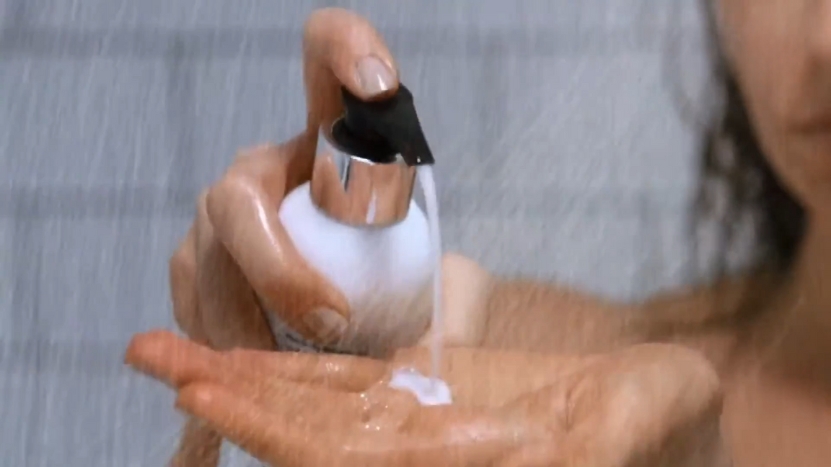 The Image Shows a Person Applying a Sulfate-Free Shampoo to Their Hand While in The Shower